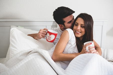 мужчина и женщина пьют кофе в постели