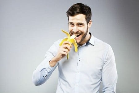 Мужчина ест банан