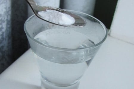 Ложка с содой над стаканом с водой