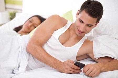 Мужчина в кровати с мобильным телефоном